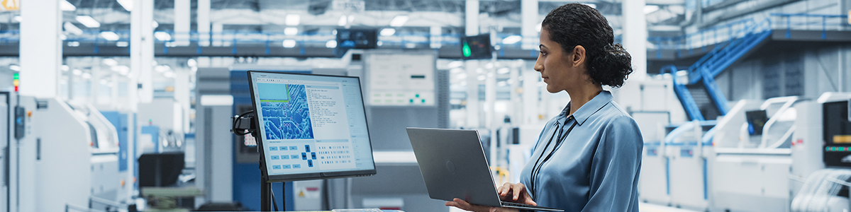 Electronics Manufacturing Technician Working on a Laptop Computer at a Factory Space.